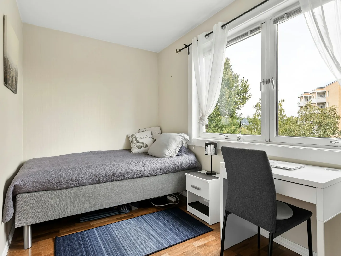 Helles möbliertes Zimmer mit Bett, Schreibtisch und Fenster