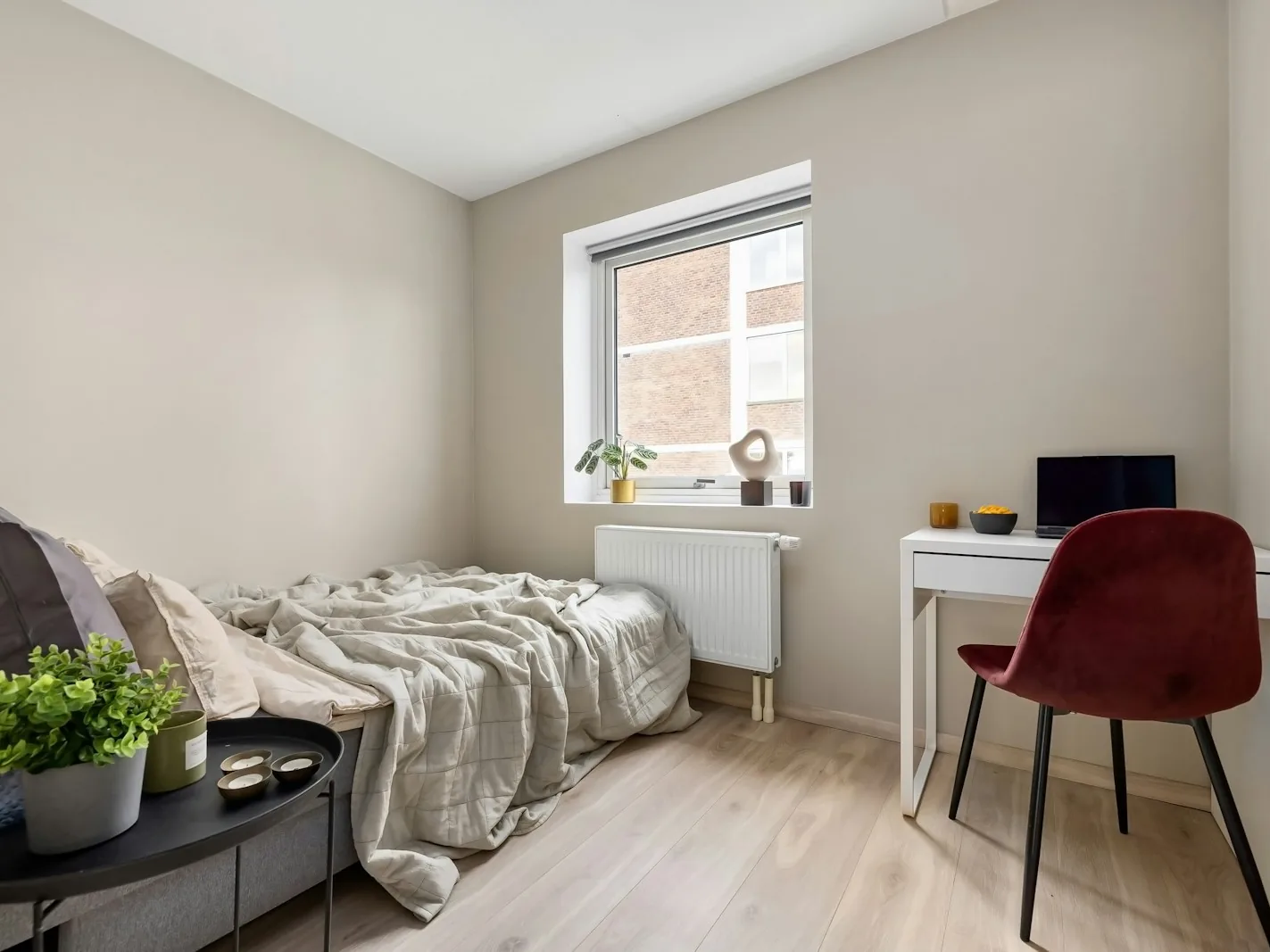 Helles möbliertes Zimmer mit Bett, Schreibtisch und Fenster