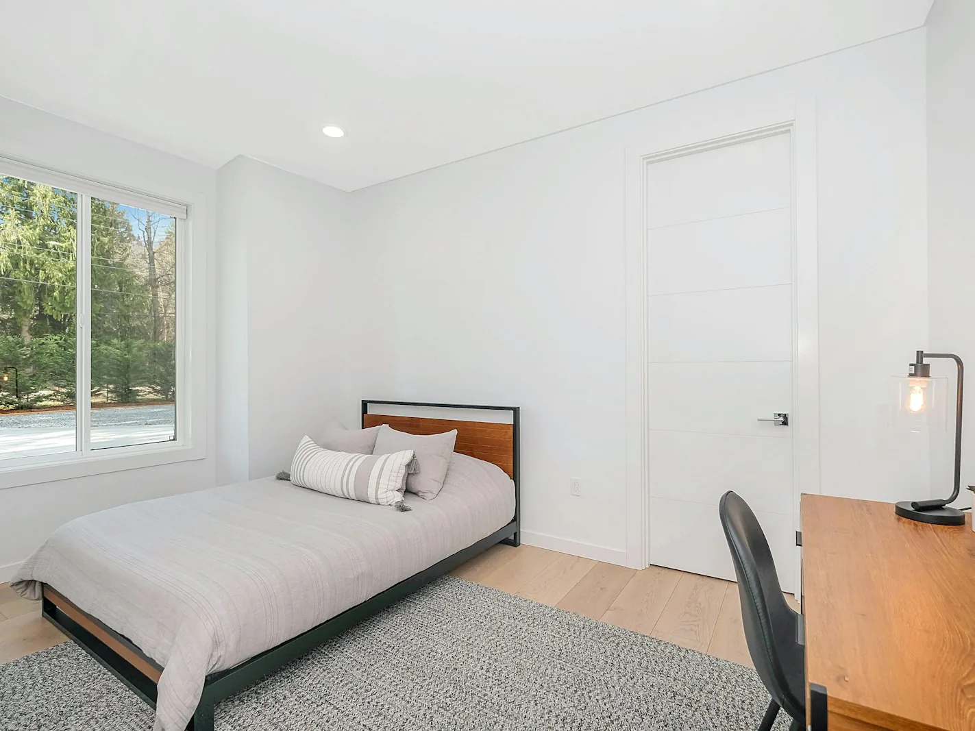 Helles möbliertes Zimmer mit Bett, Schreibtisch und Fenster